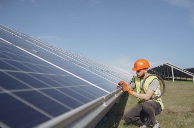 Male worker with solar batteries. Man in a protective helmet. Installing stand-alone solar panel system.